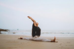 woman practising yoga on a beach