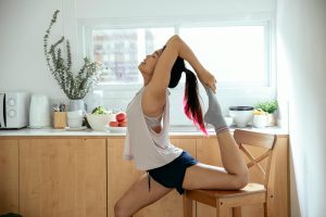 young asian woman stretching leg on wooden chair